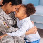 Soldier embracing child at home happily.