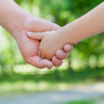 Father holds hand of little child boy in park outdoor