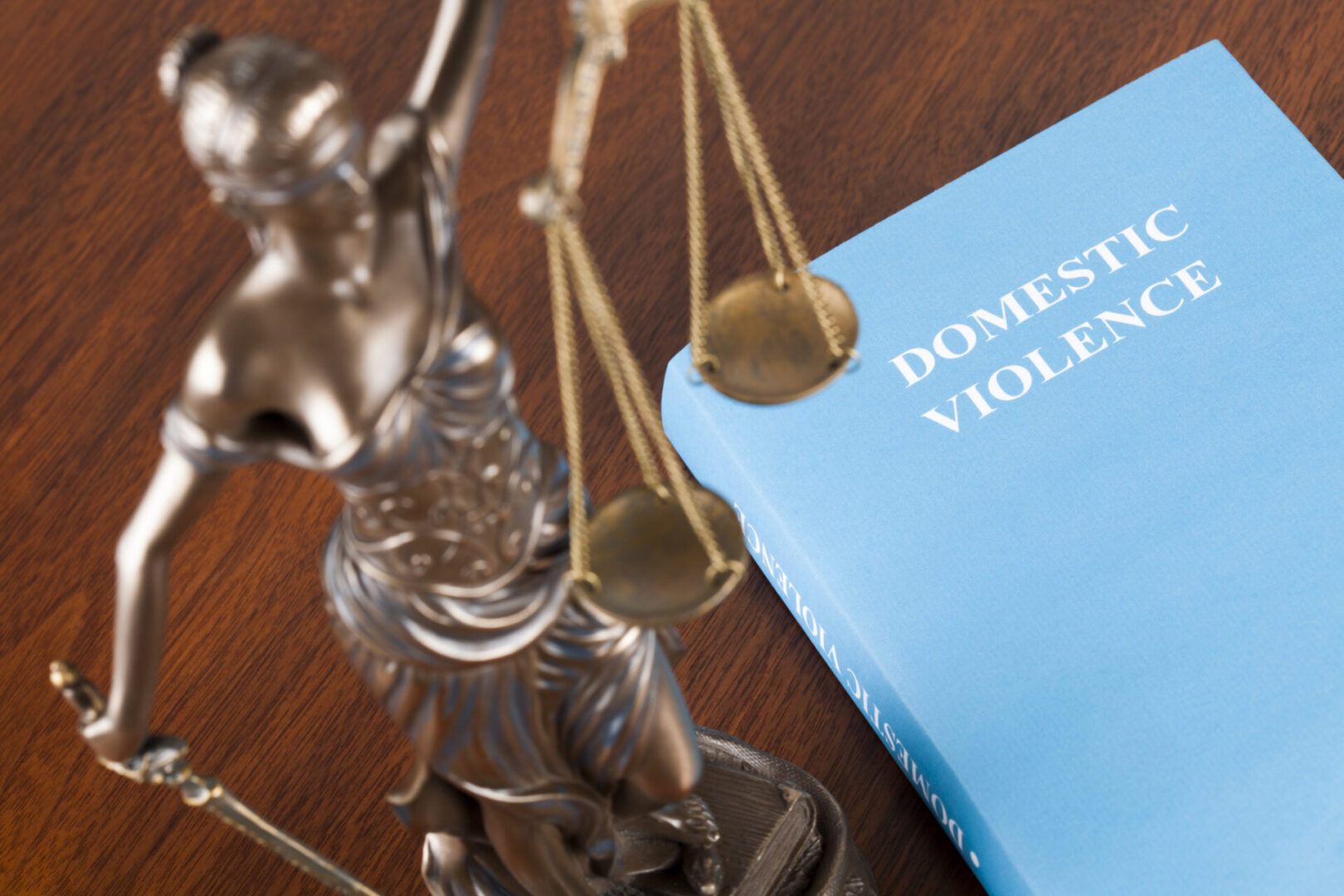 Statue of Justice beside domestic violence book.