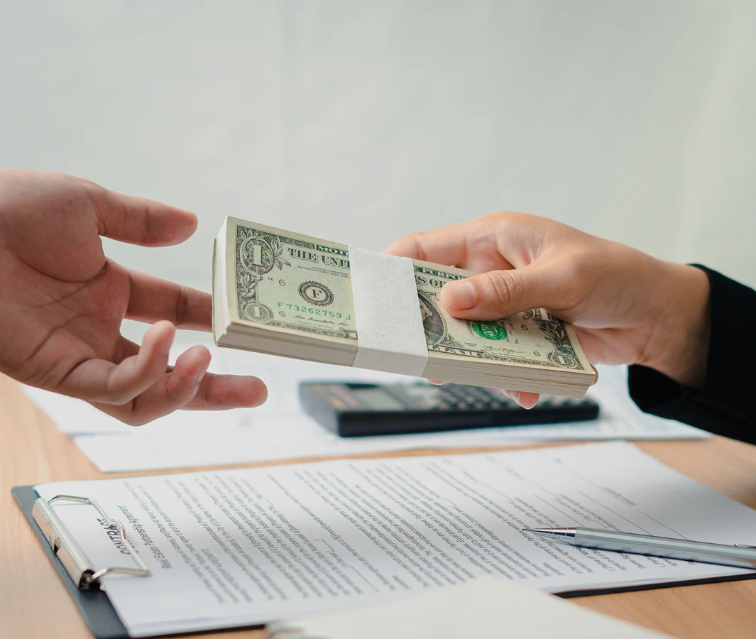 Hands exchanging stack of dollar bills.