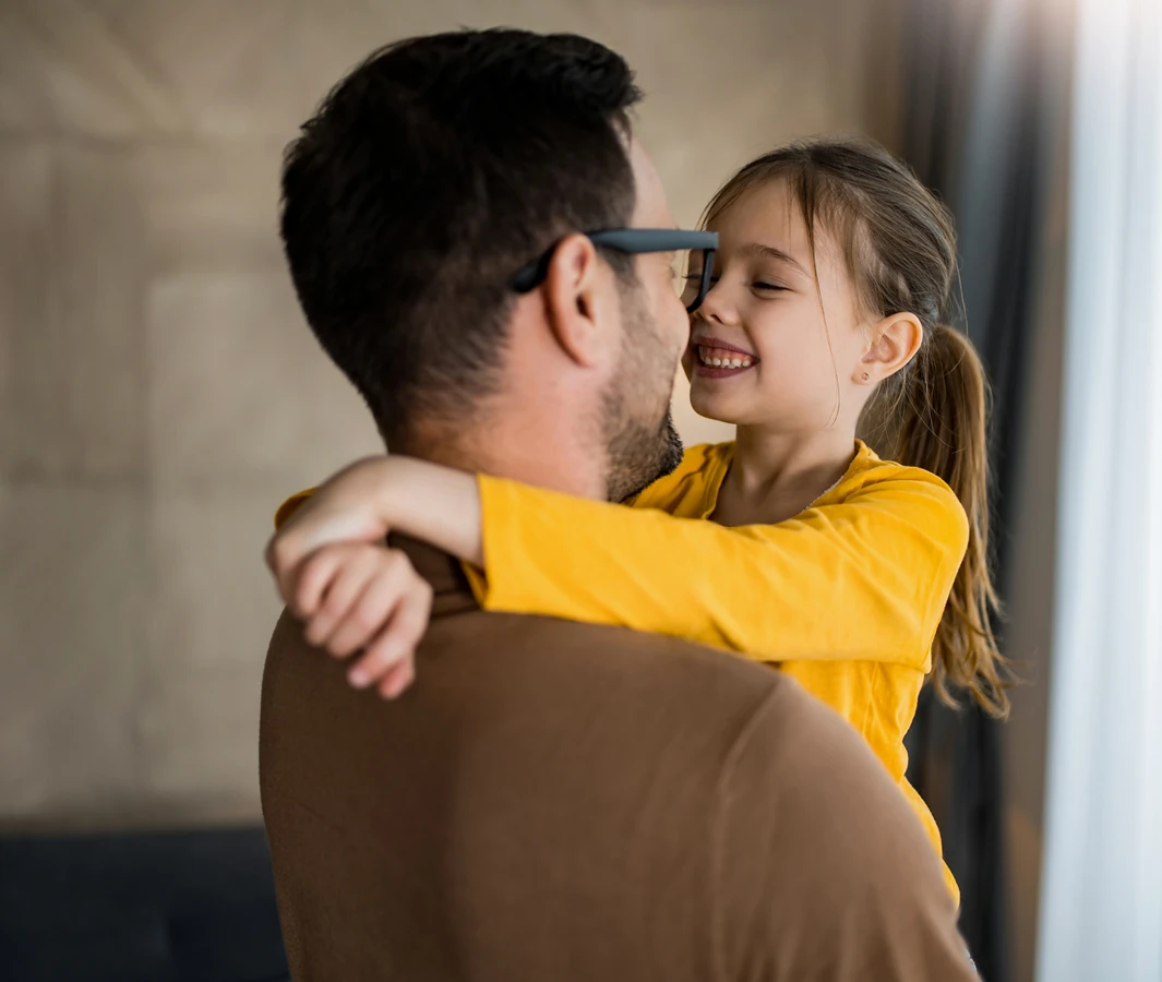 Father and daughter hugging and smiling warmly.
