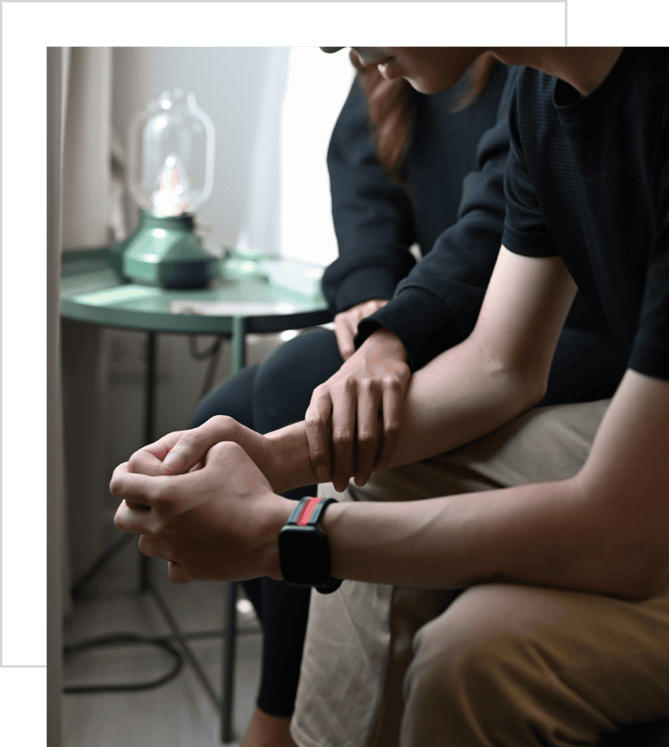 Two people sitting and holding hands gently.