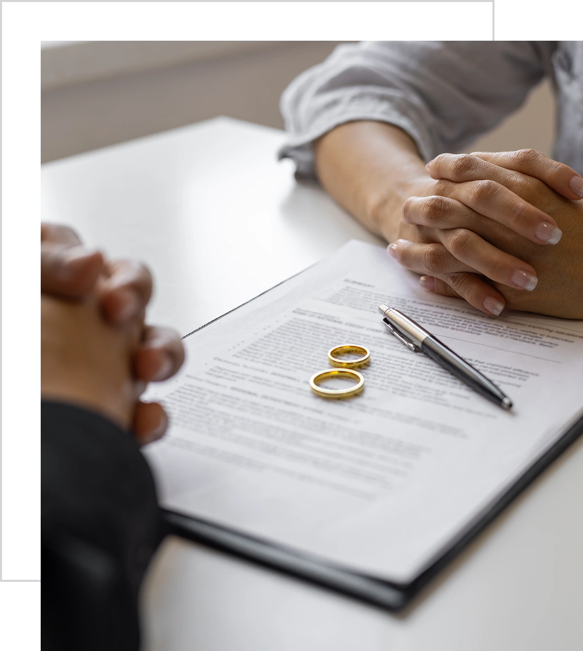 Hands, rings, and document on table.