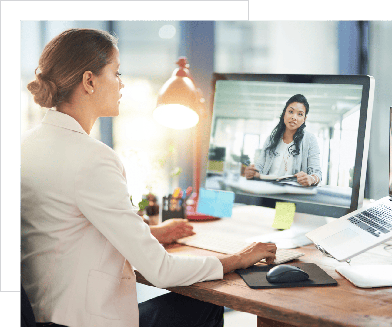 Video conference between two businesswomen at desks.